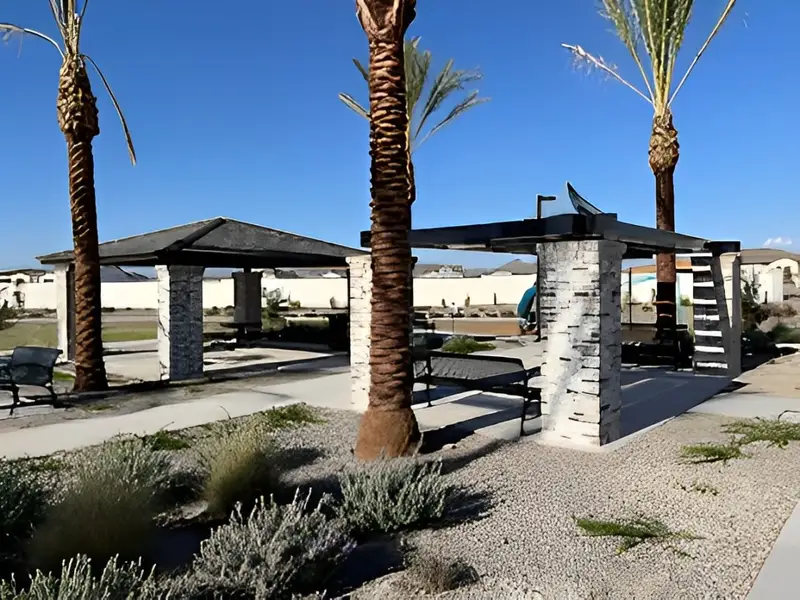 A modern park pavilion with palm trees and gravel landscaping in Grove at Lehi by Blandford Homes (Mesa, AZ).