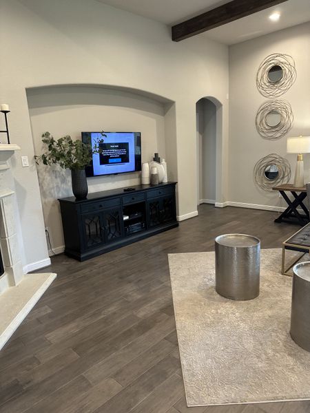 A cozy living room with wood flooring, modern decor, and stylish wall art. Dark media console complements the space. A cozy living room with wood flooring, modern decor, and stylish wall art. Dark media console complements the space.