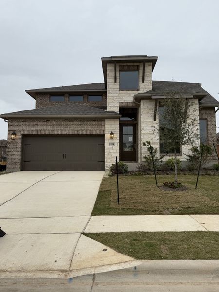 A modern stone and brick home with a neat driveway in Parkside Peninsula 50' by Perry Homes (Georgetown, TX).