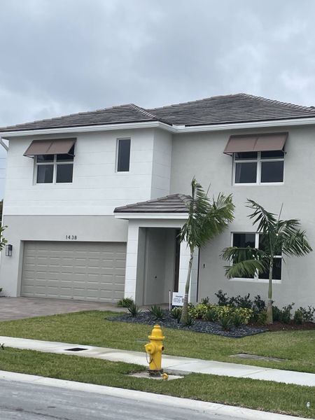 A modern two-story home with palm trees and a sleek design in Parker Pointe by D.R. Horton (Homestead, FL).