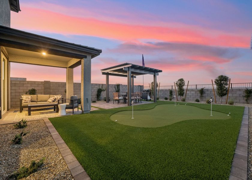 A large green lawn with a gazebo and a building in the background.