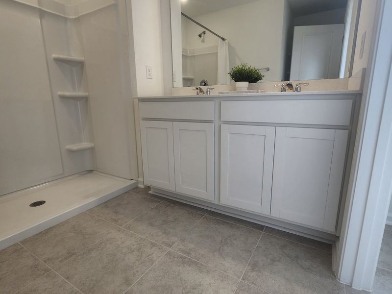 A modern bathroom featuring a sleek walk-in shower, dual sinks, and elegant white cabinetry.