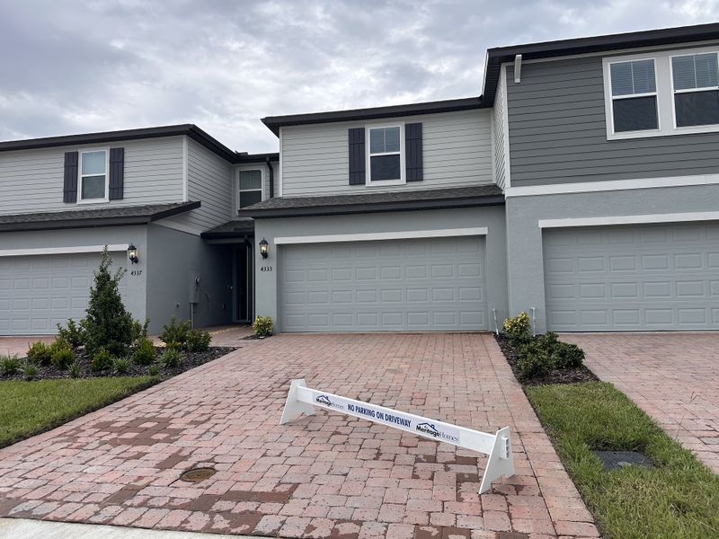 Modern gray townhomes with manicured lawns and dual garages in Eden at Crossprairie by M/I Homes (St. Cloud, FL). Modern gray townhomes with manicured lawns and dual garages in Eden at Crossprairie by M/I Homes (St. Cloud, FL).