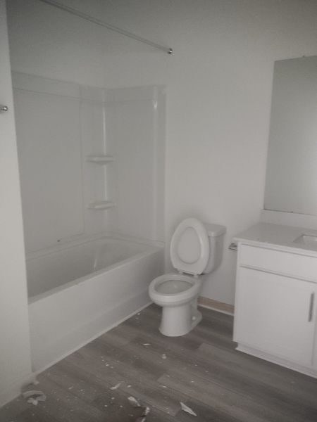 A modern bathroom features a sleek tub, white vanity, and neutral flooring for a clean, minimalist look.