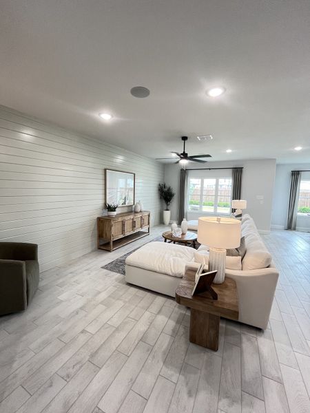 A cozy living room with wood flooring, a shiplap accent wall, and a modern sectional sofa paired with elegant decor.