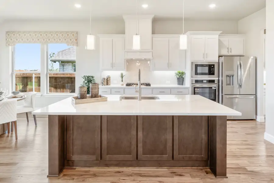 Kitchen with large dark wood island, white cabinets, quartz countertops, and stainless steel appliances on hardwood floors Kitchen with large dark wood island, white cabinets, quartz countertops, and stainless steel appliances on hardwood floors