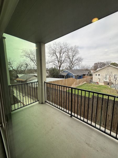 A covered balcony with sleek railing and views of a fenced backyard and neighboring homes. A covered balcony with sleek railing and views of a fenced backyard and neighboring homes.