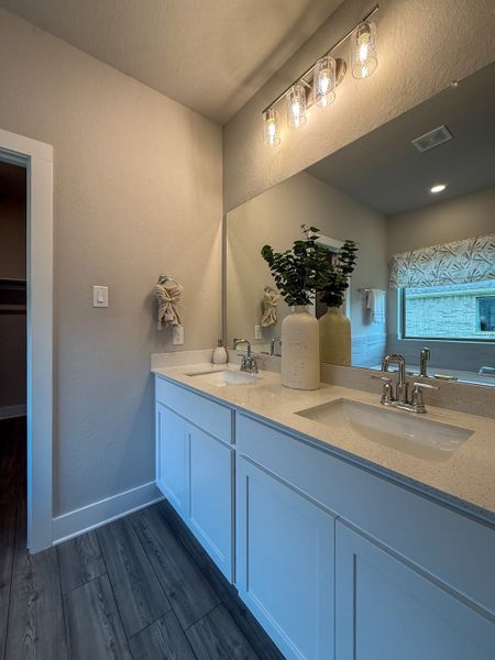 A modern bathroom featuring dual sinks, elegant lighting, and contemporary grey flooring.