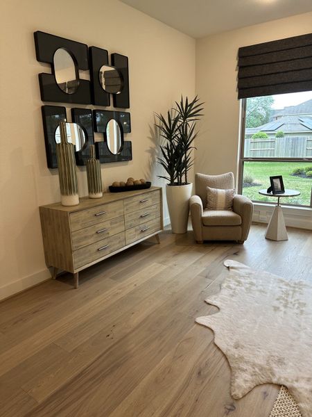 A cozy living space with sleek wood floors, modern decor, and a plush armchair by a large window.
