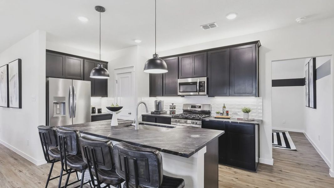 This Simpson Crossing kitchen features sleek dark cabinetry and a refined stone island, blending elegance with functionality.