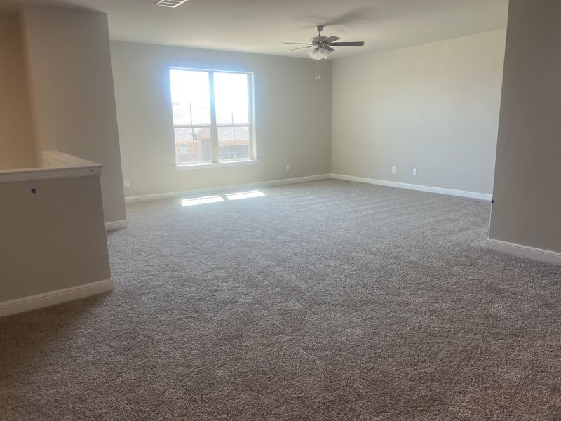 A spacious, carpeted room with neutral walls, large window, and ceiling fan, perfect for a cozy living area. A spacious, carpeted room with neutral walls, large window, and ceiling fan, perfect for a cozy living area.