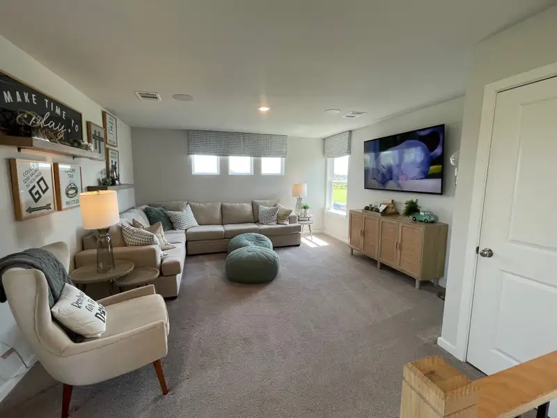A cozy living room with a large sectional, modern decor, wall-mounted TV, and soft lighting for an inviting atmosphere.