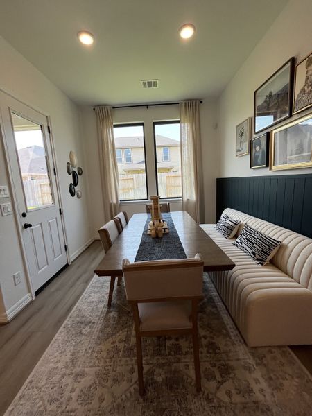 A cozy dining area with a plush banquette, modern art, and large windows for natural light. A cozy dining area with a plush banquette, modern art, and large windows for natural light.