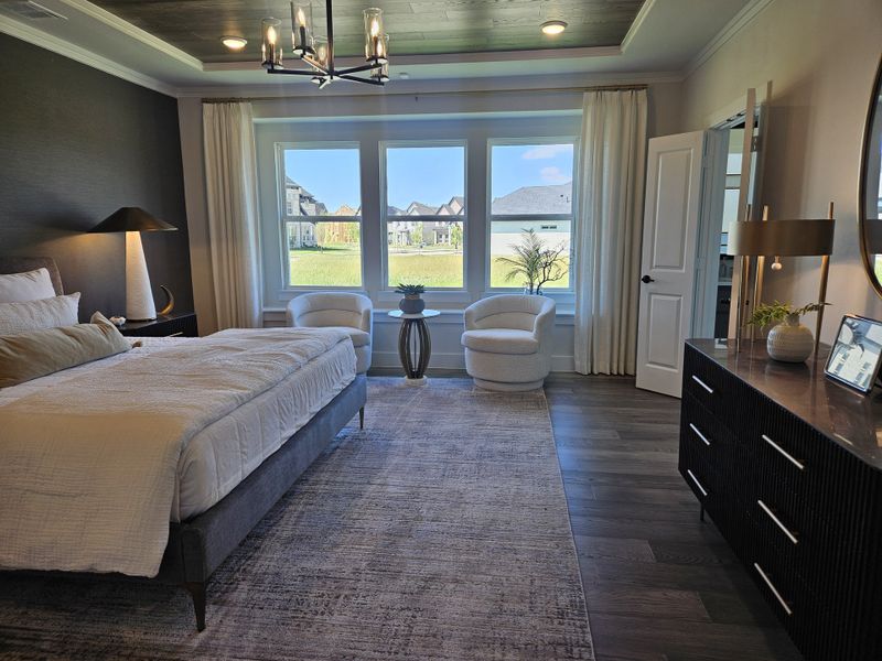 A luxurious bedroom featuring a chic chandelier, elegant drapery, and sleek furniture with a view of the outside landscape. A luxurious bedroom featuring a chic chandelier, elegant drapery, and sleek furniture with a view of the outside landscape.