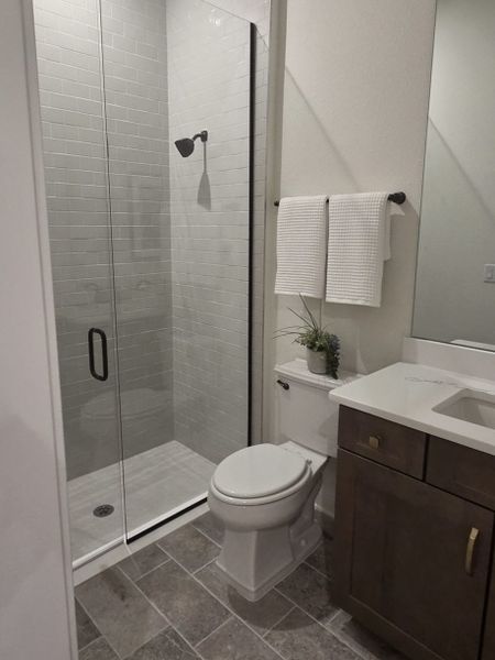A modern bathroom featuring a sleek glass shower, elegant tiles, and a stylish dark wood vanity.