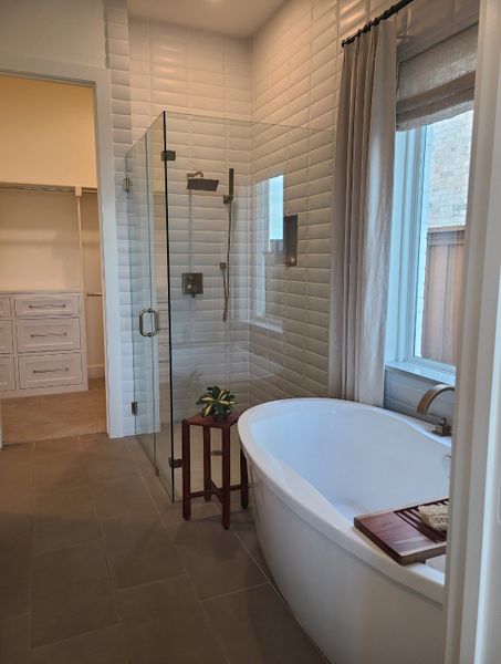A modern bathroom featuring a freestanding tub, glass shower, and white textured tiles for an elegant, serene vibe.