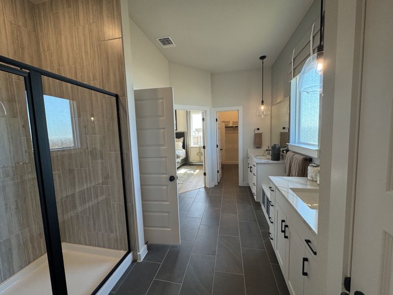 A modern bathroom with a spacious glass shower, dual sinks, sleek cabinetry, and elegant lighting.