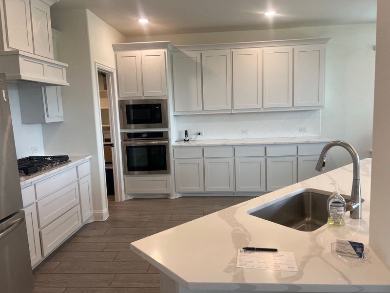 A modern kitchen featuring sleek white cabinetry, stainless steel appliances, and a spacious island with a built-in sink. A modern kitchen featuring sleek white cabinetry, stainless steel appliances, and a spacious island with a built-in sink.