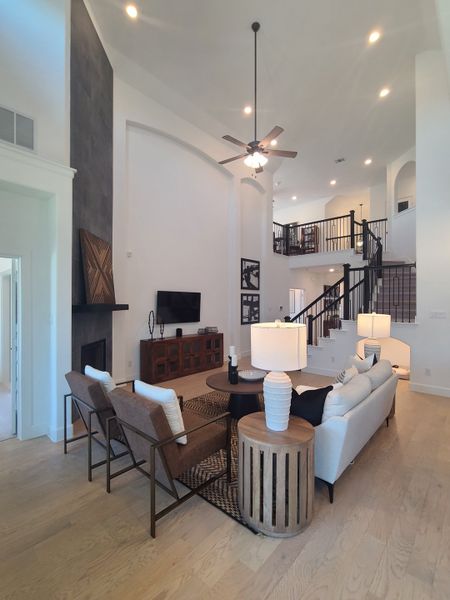A spacious living room with high ceilings, modern furnishings, and wooden floors. Features a stylish staircase and cozy lighting.