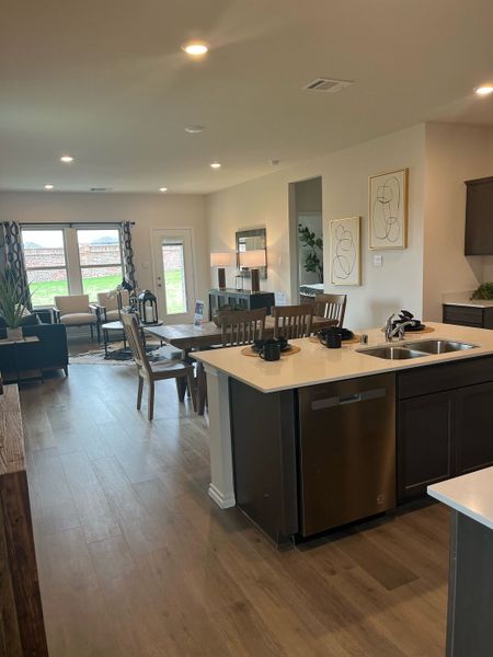 Open-concept kitchen and living area with sleek cabinetry, wooden flooring, and elegant lighting. Perfect for modern living.