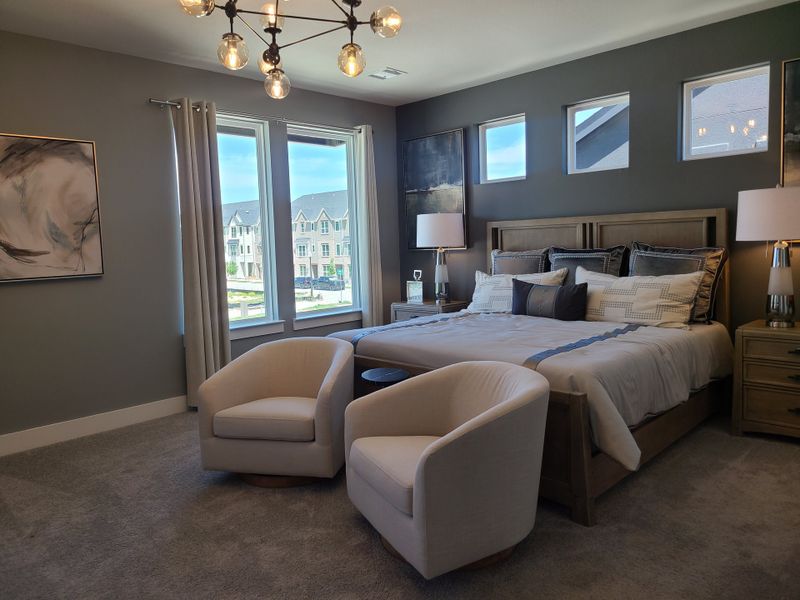 A modern bedroom with a plush bed, soft lighting, gray-toned walls, and cozy seating, creating a relaxing atmosphere. A modern bedroom with a plush bed, soft lighting, gray-toned walls, and cozy seating, creating a relaxing atmosphere.