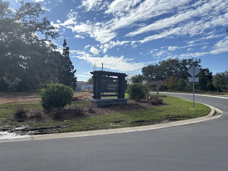 Entrance to Sunset Hills by D.R. Horton in Summerfield, FL, featuring a welcoming sign amidst lush greenery.