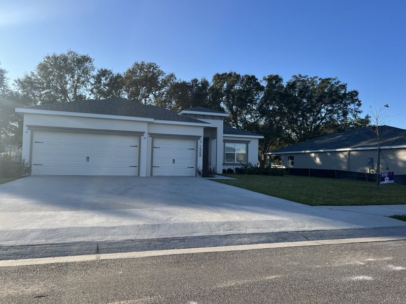 A modern home with a three-car garage and spacious driveway in Otter Woods Estates by Highland Homes of Florida (Auburndale, FL).