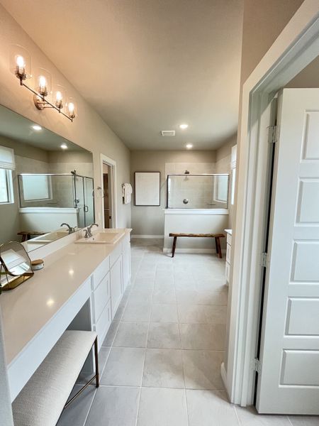 A spacious bathroom with dual sinks, a glass-enclosed shower, elegant lighting, and a chic standalone tub.