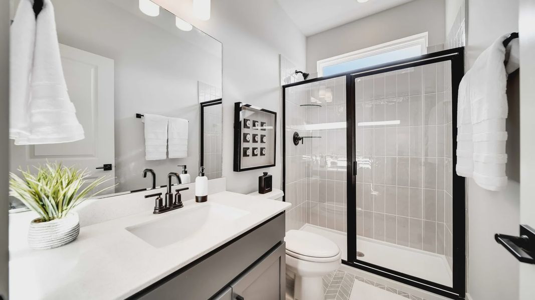 Experience sleek black fixtures and refined geometric tiles in Richvale Estates' elegant bathroom design.