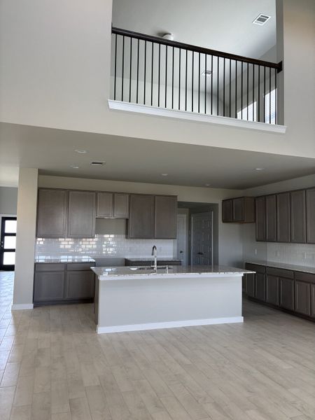 Spacious modern kitchen with gray cabinetry, sleek countertops, and an open mezzanine view above. Spacious modern kitchen with gray cabinetry, sleek countertops, and an open mezzanine view above.