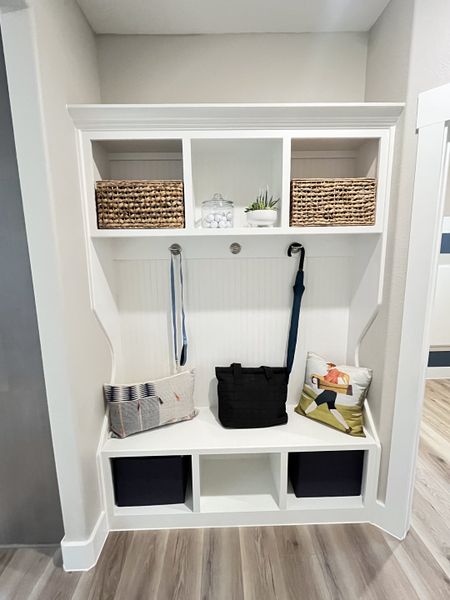 A chic mudroom nook with woven baskets, hooks, and cozy pillows, featuring sleek storage and a modern design. A chic mudroom nook with woven baskets, hooks, and cozy pillows, featuring sleek storage and a modern design.