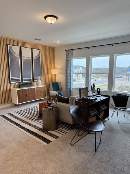 A modern living room with a wooden accent wall, stylish artwork, and large windows for natural light.