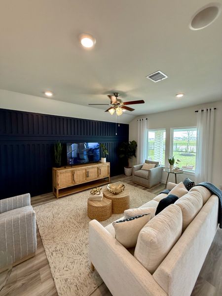 A cozy living room featuring a navy accent wall, beige sofas, and natural wood elements for a warm, inviting atmosphere.