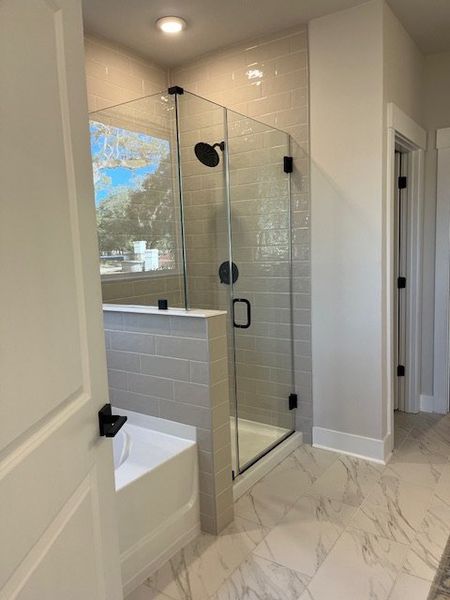 A modern bathroom featuring a glass shower, sleek subway tiles, and elegant marble flooring.