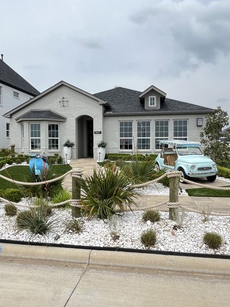 Charming white brick home with lush landscaping in Venetian by Megatel Homes (Celina, TX).