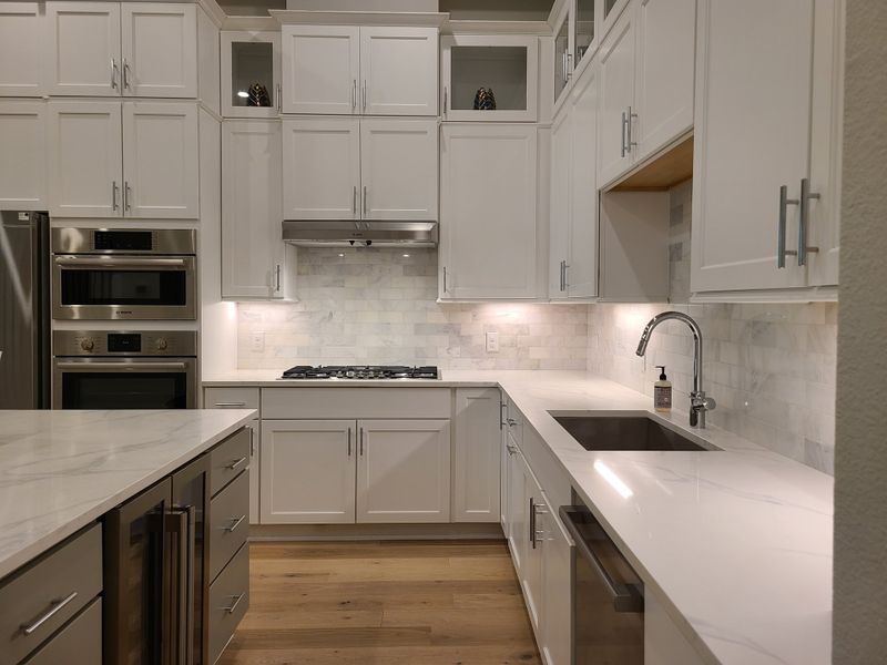 A modern kitchen with sleek white cabinetry, stainless steel appliances, and chic marble countertops. A modern kitchen with sleek white cabinetry, stainless steel appliances, and chic marble countertops.