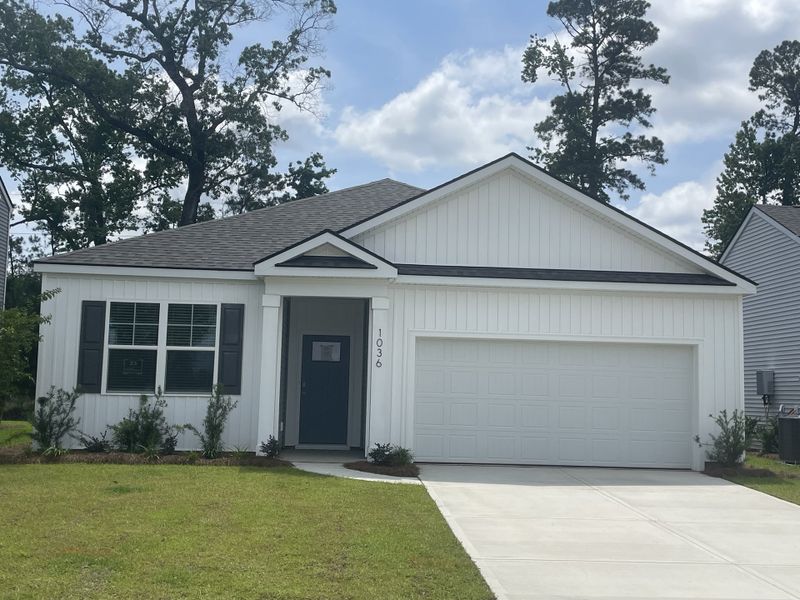 A charming white paneled home with a spacious garage and lush greenery in Pineview North by D.R. Horton (Summerville, SC).