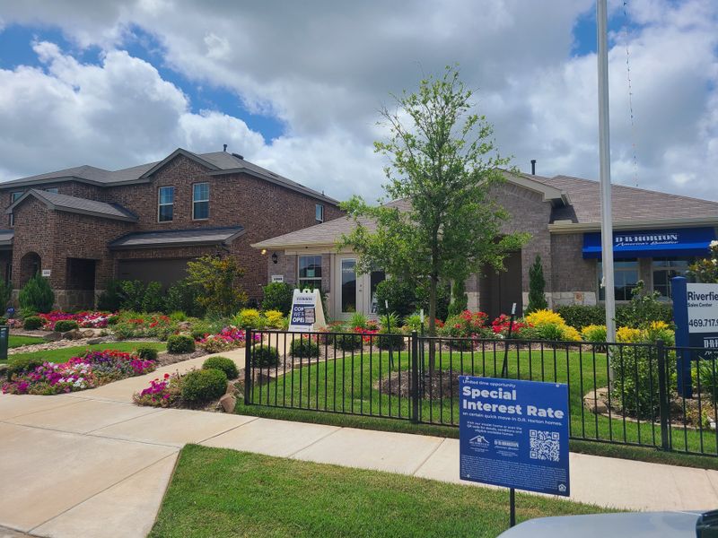 A charming brick home with vibrant landscaping in Riverfield by D.R. Horton (Josephine, TX).