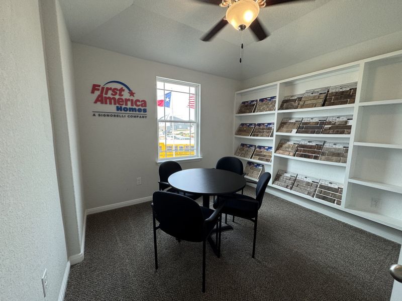 A cozy office space with a round table, chairs, and shelves displaying brick samples. Modern and inviting atmosphere.
