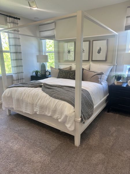 A cozy bedroom with a white canopy bed, plush carpet, and subtle decorative accents, creating a serene atmosphere.