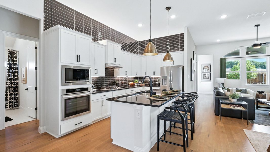 Elegant kitchen features chic black countertops, pendant lighting, and exquisite wood flooring in Green Oaks Preserve. Elegant kitchen features chic black countertops, pendant lighting, and exquisite wood flooring in Green Oaks Preserve.