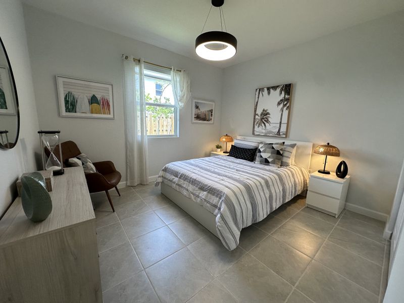 A cozy bedroom with modern decor, featuring a striped bed, sleek furniture, and warm lighting accents.
