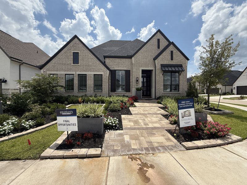 A charming light brick home with elegant landscaping in Sienna by Highland Homes, Missouri City, TX.