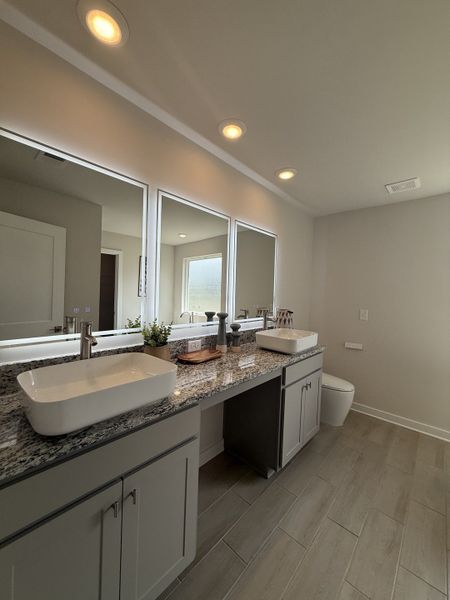A sleek bathroom with dual vessel sinks, granite countertops, and modern LED mirror lighting. A sleek bathroom with dual vessel sinks, granite countertops, and modern LED mirror lighting.
