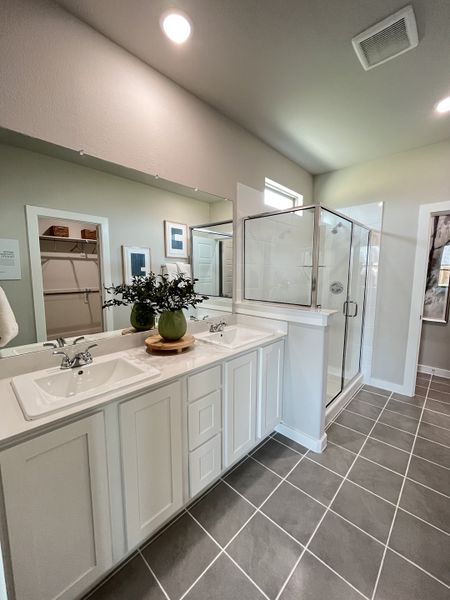A contemporary bathroom featuring dual sinks, a spacious glass shower, and sleek gray tiled flooring. A contemporary bathroom featuring dual sinks, a spacious glass shower, and sleek gray tiled flooring.