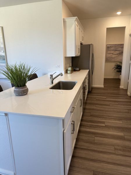 A modern kitchen featuring sleek white cabinetry, stainless steel appliances, and elegant wood flooring. A modern kitchen featuring sleek white cabinetry, stainless steel appliances, and elegant wood flooring.