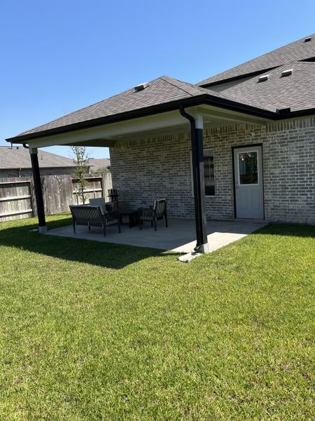 A charming covered patio in a lush backyard in Massey Oaks by CastleRock Communities (Pearland, TX).
