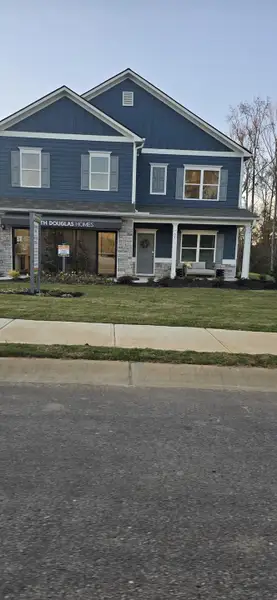 Charming blue two-story home with stone accents in Roxeywood Park by Smith Douglas Homes (Winder, GA).