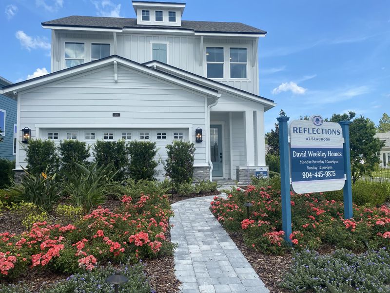 A beautiful white home with lush landscaping in Reflections 50' Front Load by David Weekley Homes, Ponte Vedra Beach, FL.