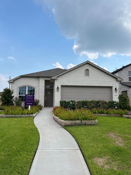 A charming white brick home with manicured landscaping in Tamarron by D.R. Horton (Fulshear, TX).